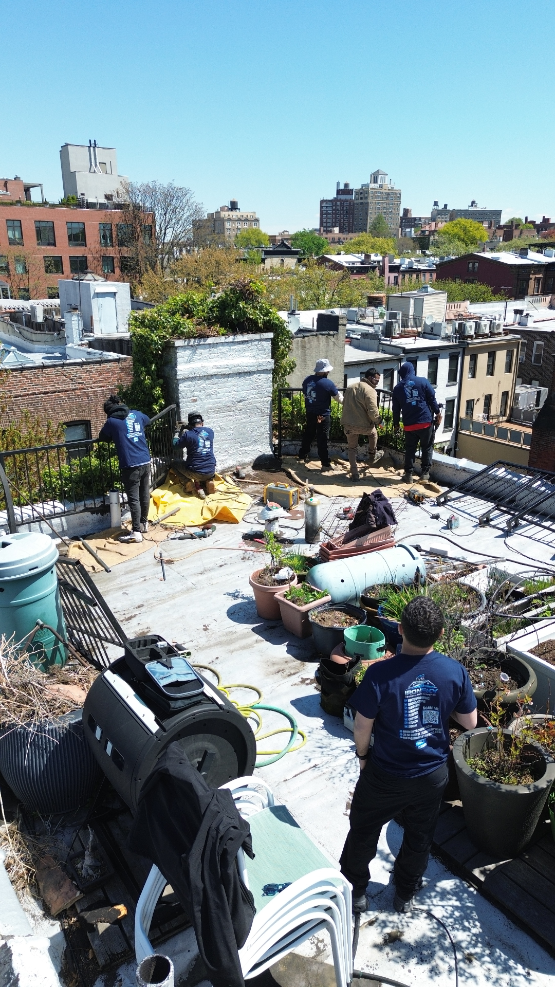 IronSky crew waterproofing a Brooklyn rooftop garden with NYC skyline in the background