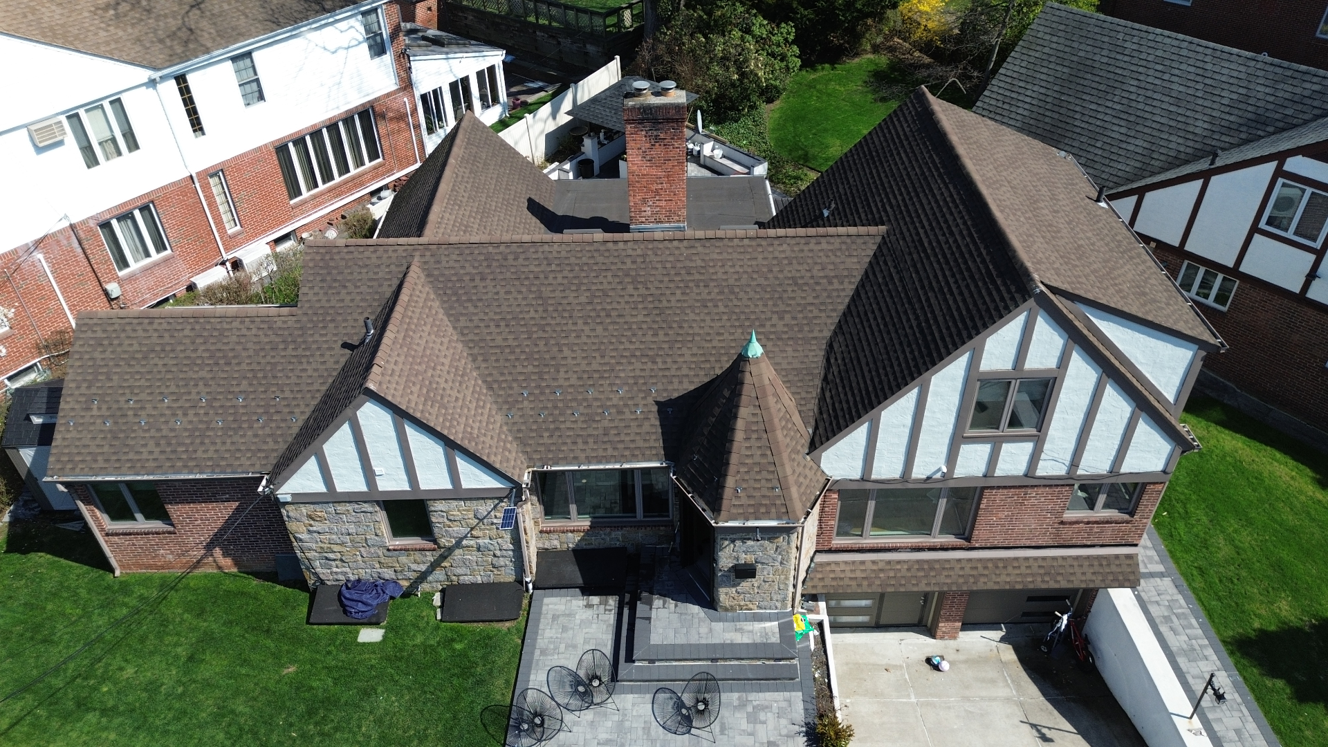 Drone aerial view of a finished brown architectural shingle roof on a Tudor-style NYC home by IronSky